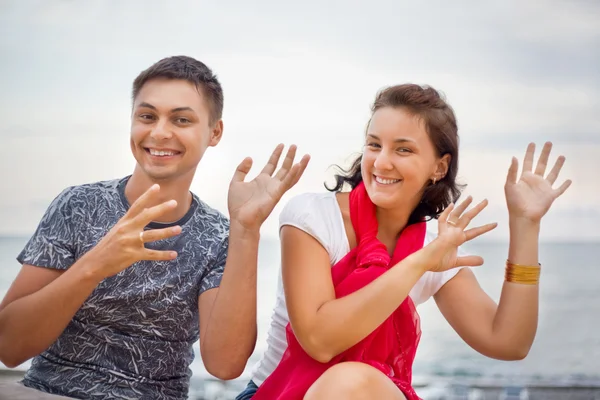 Gülümseyen adam ve genç güzel kadın plajda otururken dans — Stok fotoğraf