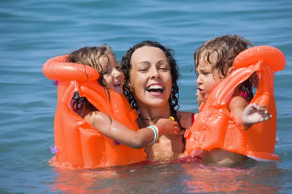 Due bambine che fanno il bagno in giubbotti di salvataggio con giovane donna in piscina — Foto Stock