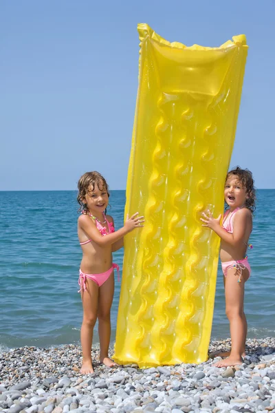 两个小女孩站在海滩上，有充气膜结构的控制权 — 图库照片