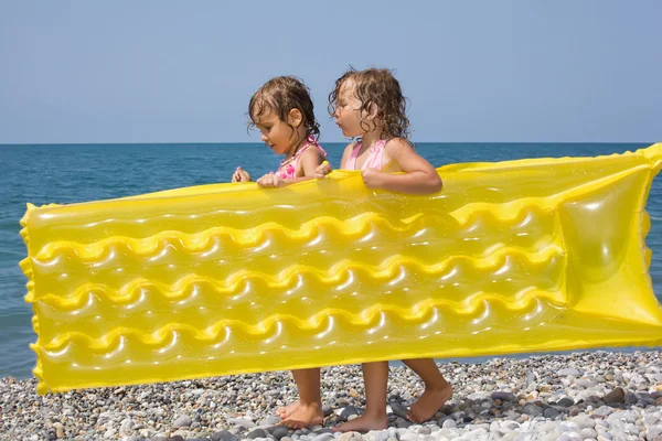 Two pretty little girls bearing in hands inflatable mattress on — Stock Photo, Image