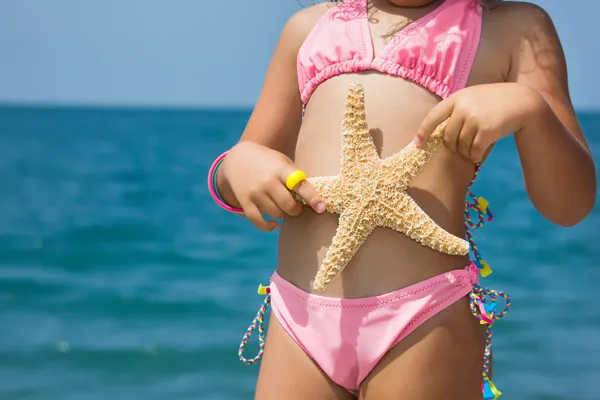 Corpo di bambina con stelle marine sulla spiaggia — Foto Stock