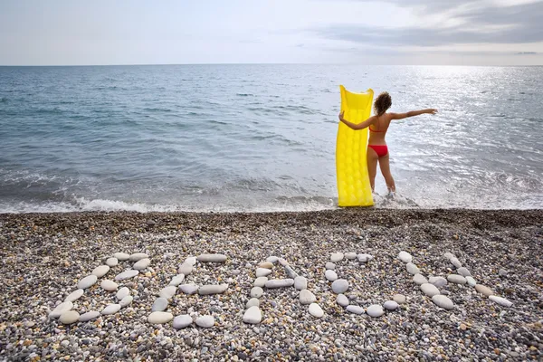 Napis z kamieniami plaży na kamienistym wybrzeżu, młoda kobieta z — Zdjęcie stockowe
