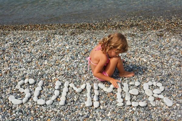 Petite fille est assise sur la plage — Photo