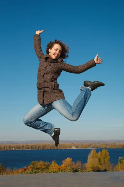 Menina de casaco e jeans no salto — Fotografia de Stock