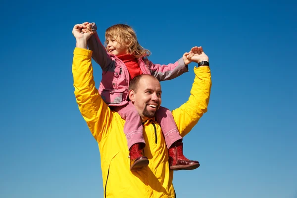 Cheerful little girl sits on shoulders at man — Stock Photo, Image