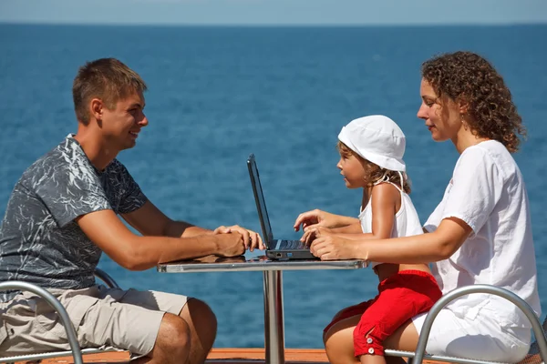 Dizüstü bilgisayar ile deniz üzerinde aile — Stok fotoğraf