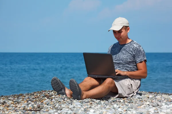 Чоловік на березі моря з ноутбуком — стокове фото