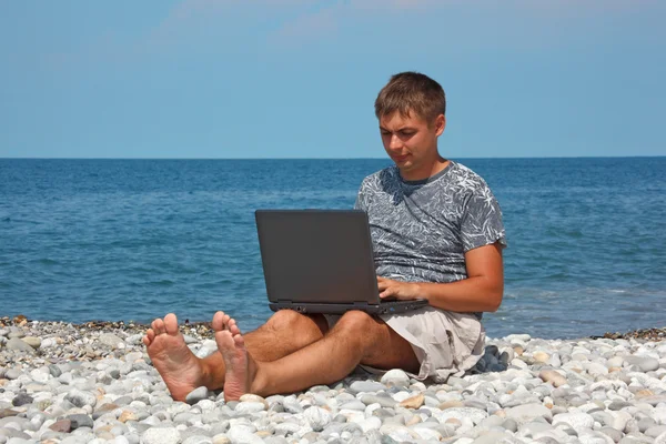 Чоловік на березі моря з ноутбуком — стокове фото