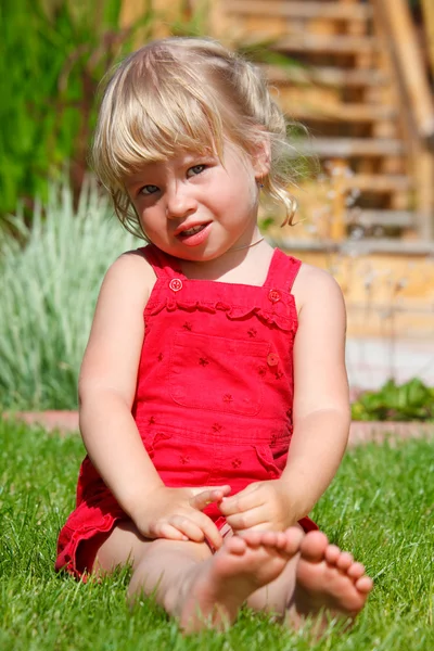 Το κοριτσάκι που κάθεται σε έναν χορτοτάπητα — Φωτογραφία Αρχείου