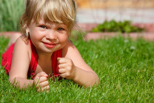 Den lilla flickan ligger på en gräsmatta — Stockfoto