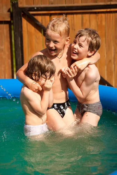Tres niños juegan en piscina inflable — Foto de Stock