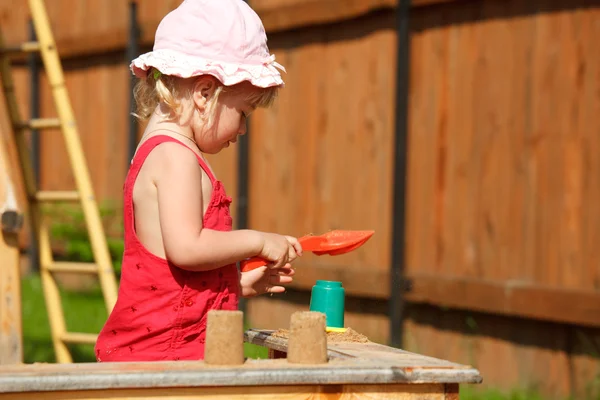 Het meisje speelt aan een sandbox. horizontale indeling. — Stockfoto