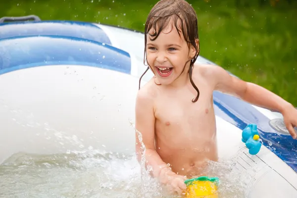 A menina joga na piscina inflável um dia ensolarado . — Fotografia de Stock