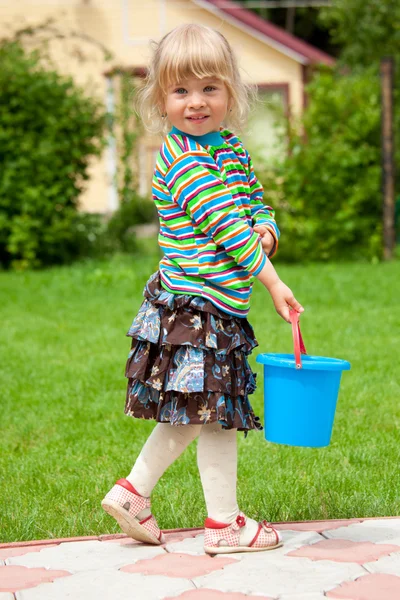 A menina em um jardim com um balde de brinquedo — Fotografia de Stock