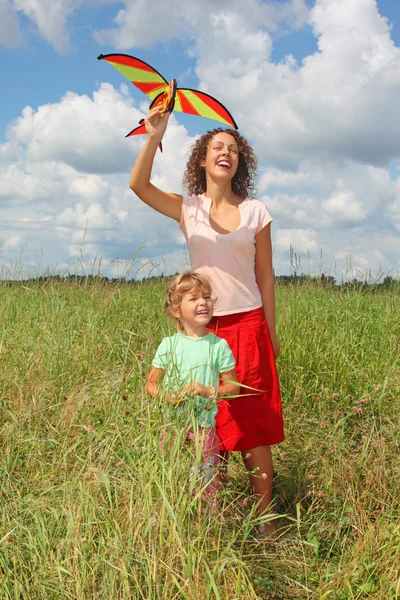 Jeune femme et petite fille joue au cerf-volant sur prairie — Photo