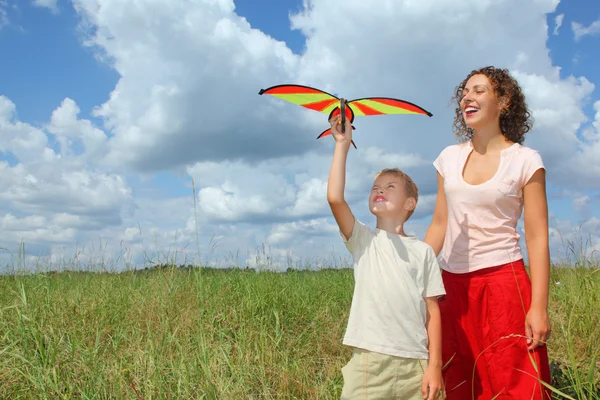 Ung kvinna och en pojke spelar kite på äng — Stockfoto