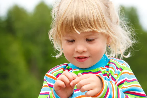 Портрет маленькой девочки в полосатой одежде с серьгами в парке . — стоковое фото