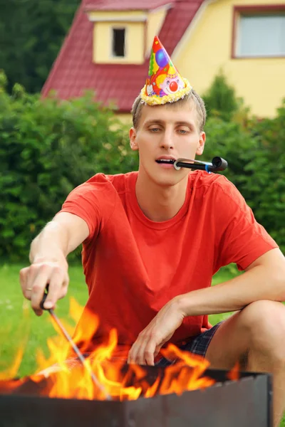Молодой человек с клеветой возле жаровни на пикнике, с днем рождения папа — стоковое фото