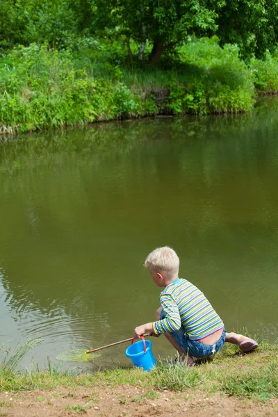 The boy with a net on the bank of lake — Stock Photo, Image