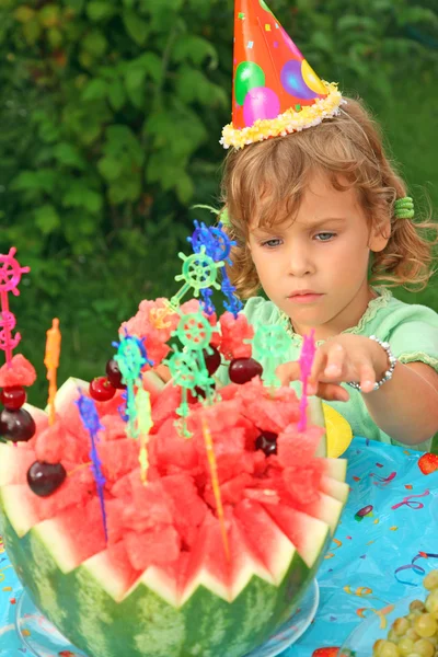 Little girl in cap eats fruit in garden, happy birthday — Stock Photo, Image