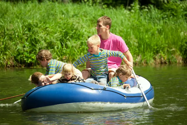 Дети под присмотром катаются на надувной лодке — стоковое фото