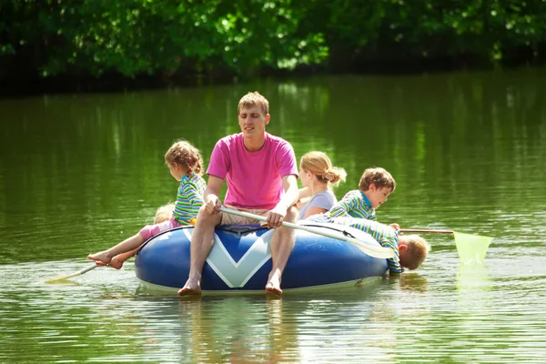 Дети и взрослые плавают на надувной лодке в солнечный день — стоковое фото
