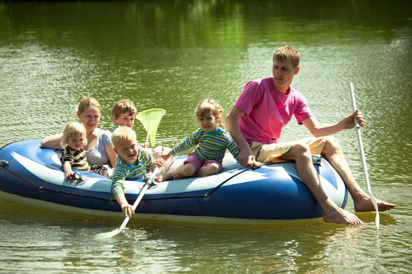Bambini e adulti galleggiano su una barca gonfiabile e pescano una rete . — Foto Stock