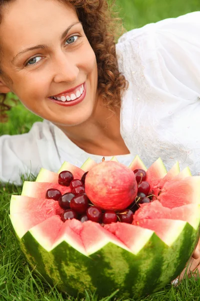 Junge schöne Frau mit Früchten, die auf dem Rasen liegen — Stockfoto