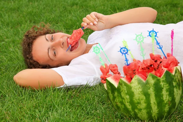 Mladá krásná žena jí meloun ležící na alawn — Stock fotografie