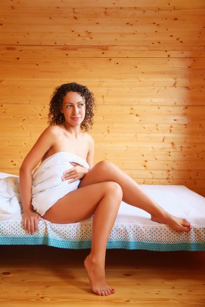 Schöne heiße Frau sitzt auf dem Bett in gemütlichen Holzzimmer — Stockfoto