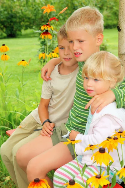 Barn som sitter på bänken i trädgården — Stockfoto