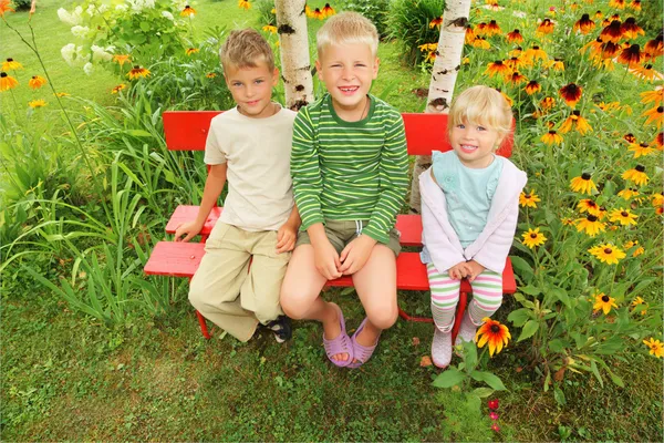 Children sitting on bench in garden — Stock Photo, Image