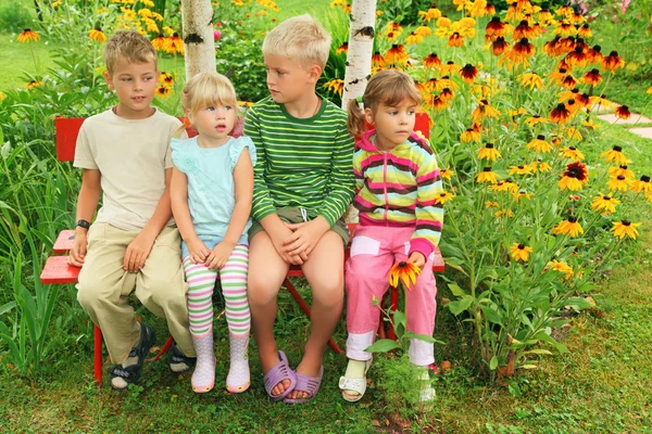 Niños sentados en el banco en el jardín — Foto de Stock