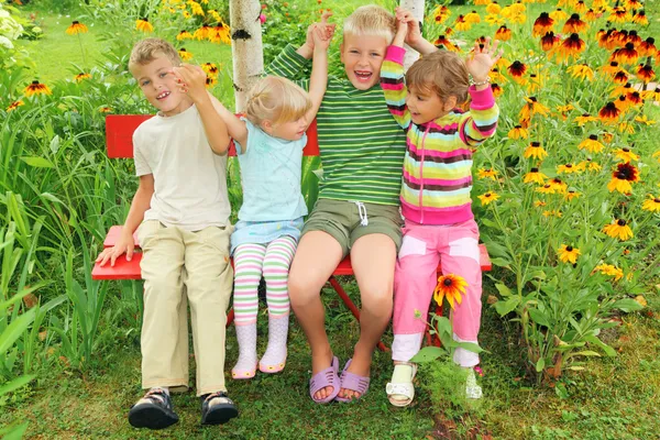 Crianças que se sentam no banco no jardim, tendo unido mãos — Fotografia de Stock