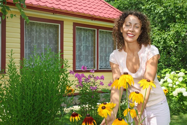 Молода жінка доглядає за квітами в саду біля будинку — стокове фото
