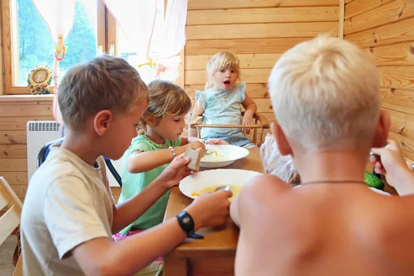 Kinder essen hinterm Tisch — Stockfoto