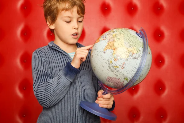 Pojke pekande finger på världen. porträtt på röd — Stockfoto