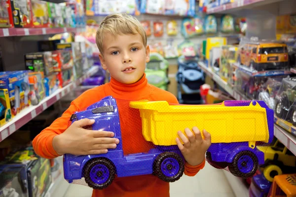 Pojken i butik med leksaksbil i händer — Stockfoto