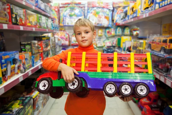 O menino na loja com o grande modelo do caminhão em mãos — Fotografia de Stock