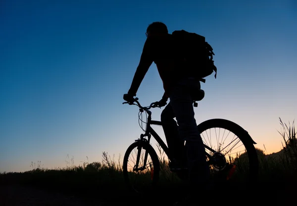 Silhueta do ciclista contra o céu escuro — Fotografia de Stock