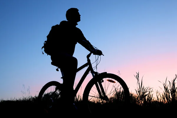 Silueta cyklistů proti západu slunce obloha — Stock fotografie