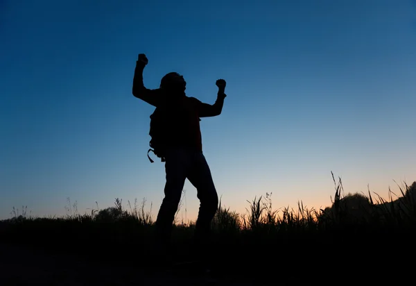 Silhouette of man with rised hands on dark sky — Stock Photo, Image