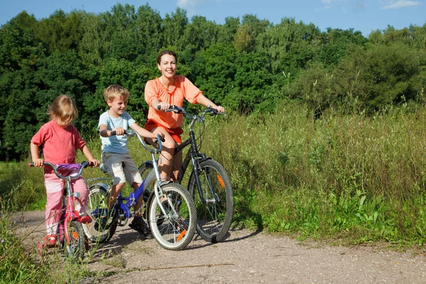 Мать с сыном и дочерью катаются на велосипедах за городом — стоковое фото