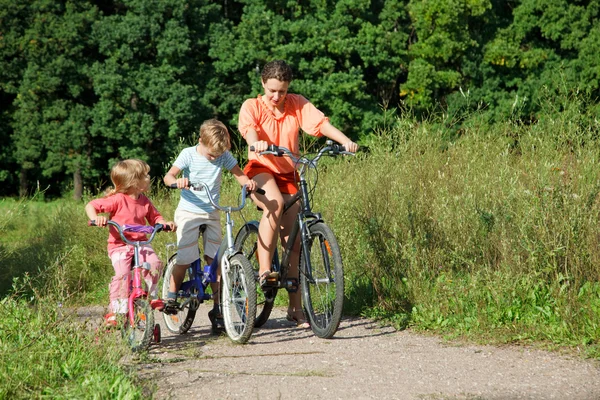 Mother with son and daughter ride bikes outside the city — Stock Photo, Image