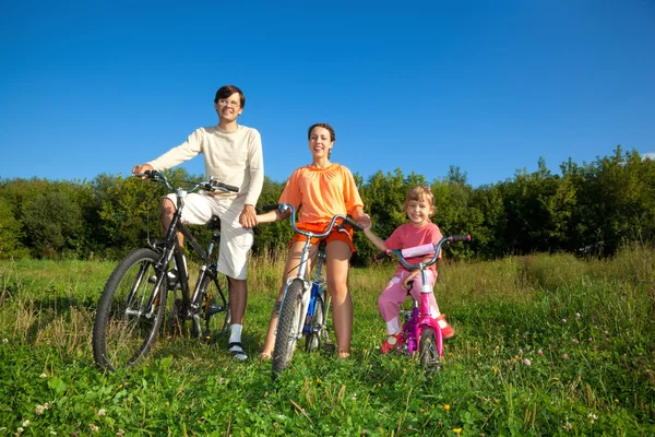 Pais com a filha em bicicletas no parque um dia ensolarado. Manter — Fotografia de Stock