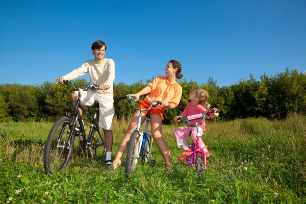 Familia de tres personas en bicicleta en el país. Mamá con un... — Foto de Stock