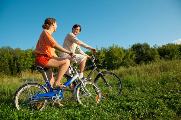 The girl and the man go for a drive on bicycles in a sunny day — Stock Photo, Image