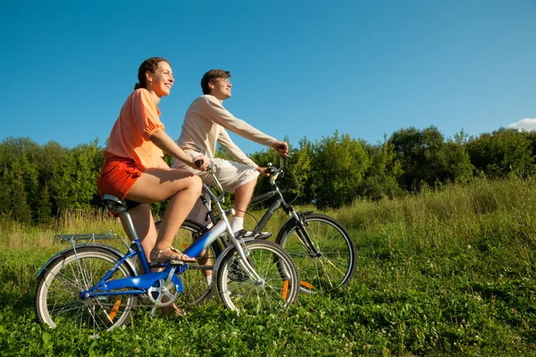 Het meisje en de man gaan voor een station op de fiets in een zonnige dag — Stockfoto