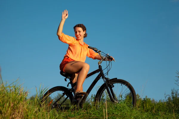 A menina acena uma mão sentada em uma bicicleta — Fotografia de Stock