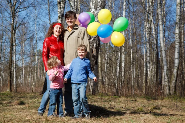 Родители с дочерью и сыном гуляют в парке с воздушными шарами — стоковое фото